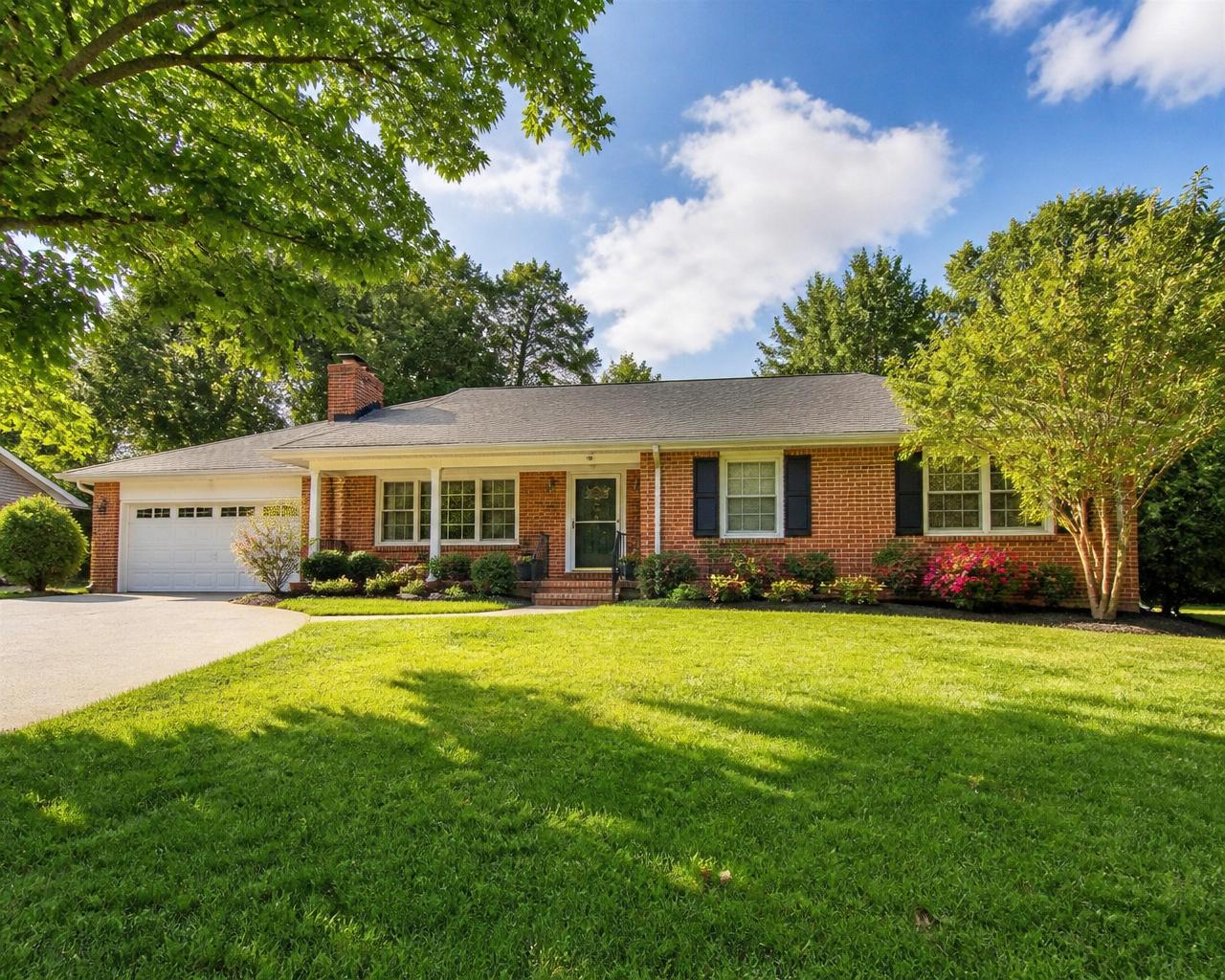 A pleasant sunny single-level home with green lawn and mature trees